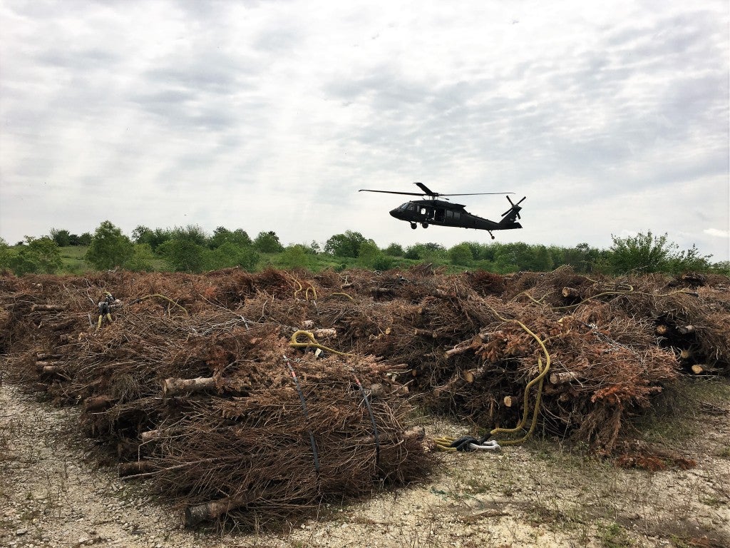 Blackhawk helicopter picks up a bundle of Christmas trees.