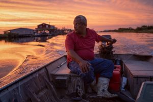 Gleason Alexis, a shrimper, drives his boat at sunset.